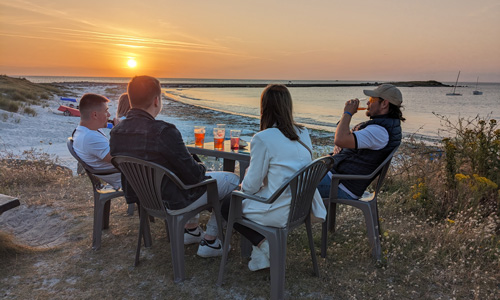 Amis buvant un verre au coucher du soleil près de la plage du Curnic
