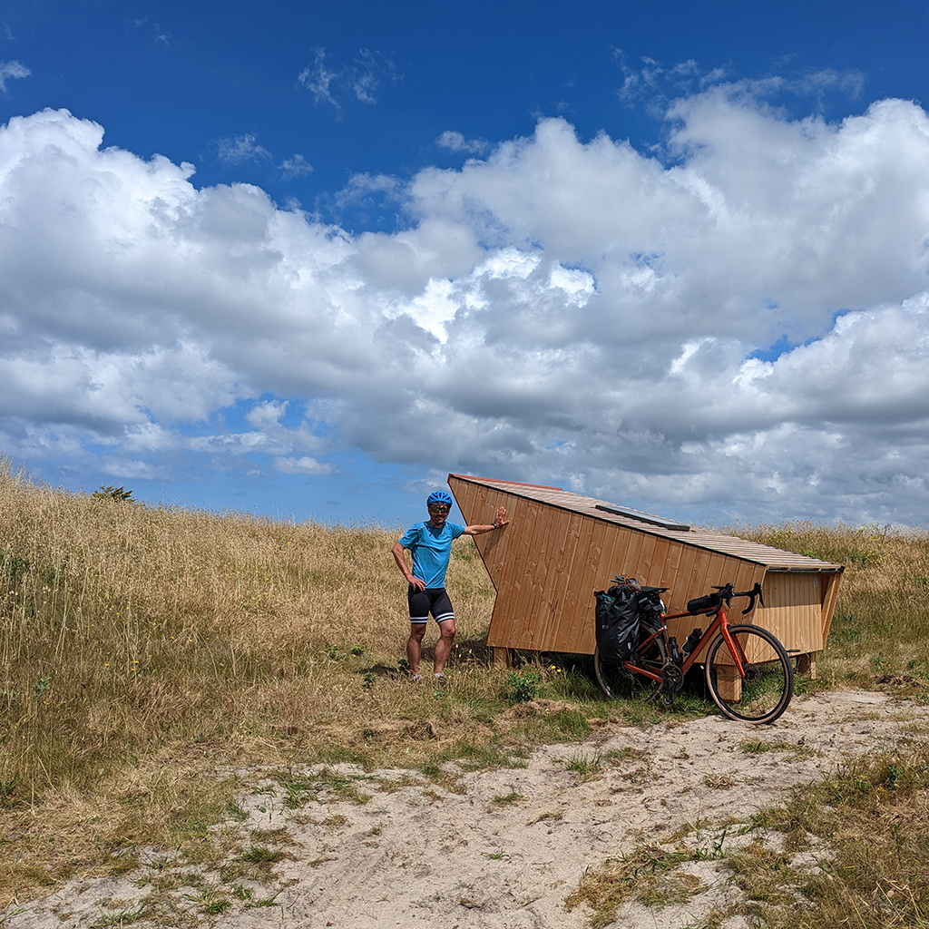 Cycliste près d'une cabane étape en bois dans les dunes