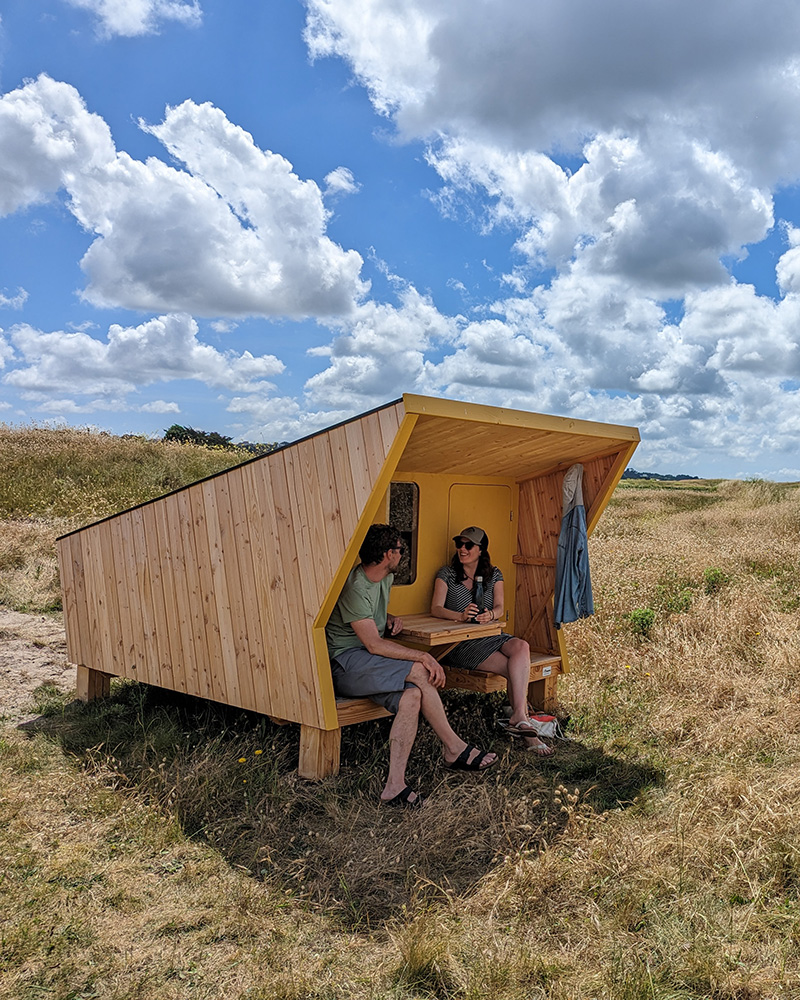 Couple de vacanciers devant une cabane étape en bois sur les dunes