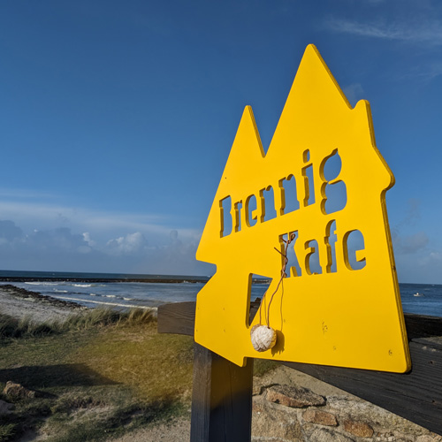 Enseigne jaune en bois du Brennig Kafe au bord de la mer